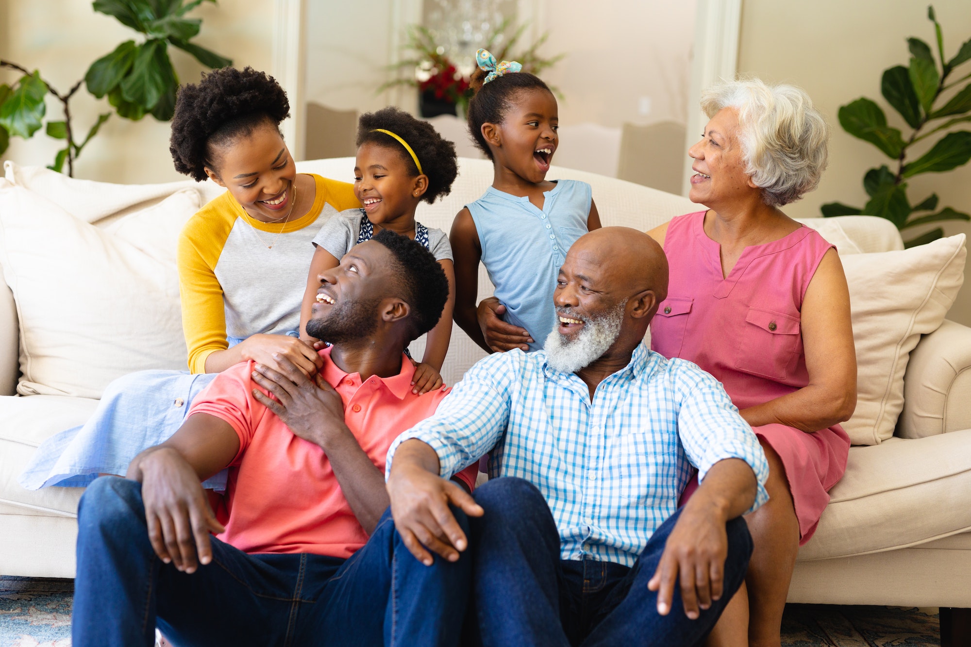 African american three generation family smiling looking at each other sitting on couch at home